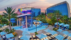 A water park area with a water slide, pool, and lounge chairs.