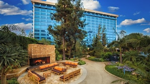 Un hotel con chimenea de piedra, zona de estar exterior y vistas a un edificio moderno.