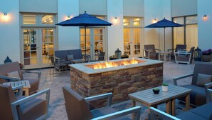 An outdoor patio with stone fire pit, seating, and umbrellas. - Detroit Marriott Southfield (Southfield)