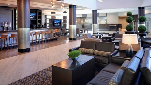 A modern hotel lobby with a bar area, seating arrangements, and a television screen. - Detroit Marriott Southfield (Southfield)