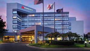 A Marriott hotel with a modern design, featuring a prominent entrance and multiple flags. - Detroit Marriott Southfield (Southfield)