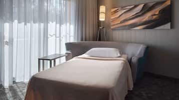 A hotel room with a bed, a bedside table, a lamp, and a painting on the wall.