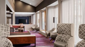 A modern living room with a fireplace, comfortable seating, and a large window with curtains. - Courtyard by Marriott Mahwah (Mahwah)