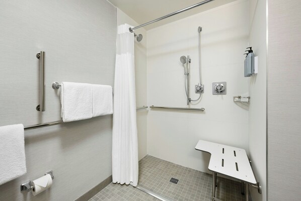 A modern shower area with a glass door, a white towel rack, a hand dryer, and a showerhead. - Courtyard by Marriott Mahwah (Mahwah)