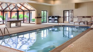 A swimming pool with a glass enclosure, a reception area, and a view of greenery outside. - Courtyard by Marriott Mahwah (Mahwah)