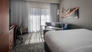 A hotel room with a large bed, a desk, a chair, and a sofa. - Courtyard by Marriott Mahwah (Mahwah)