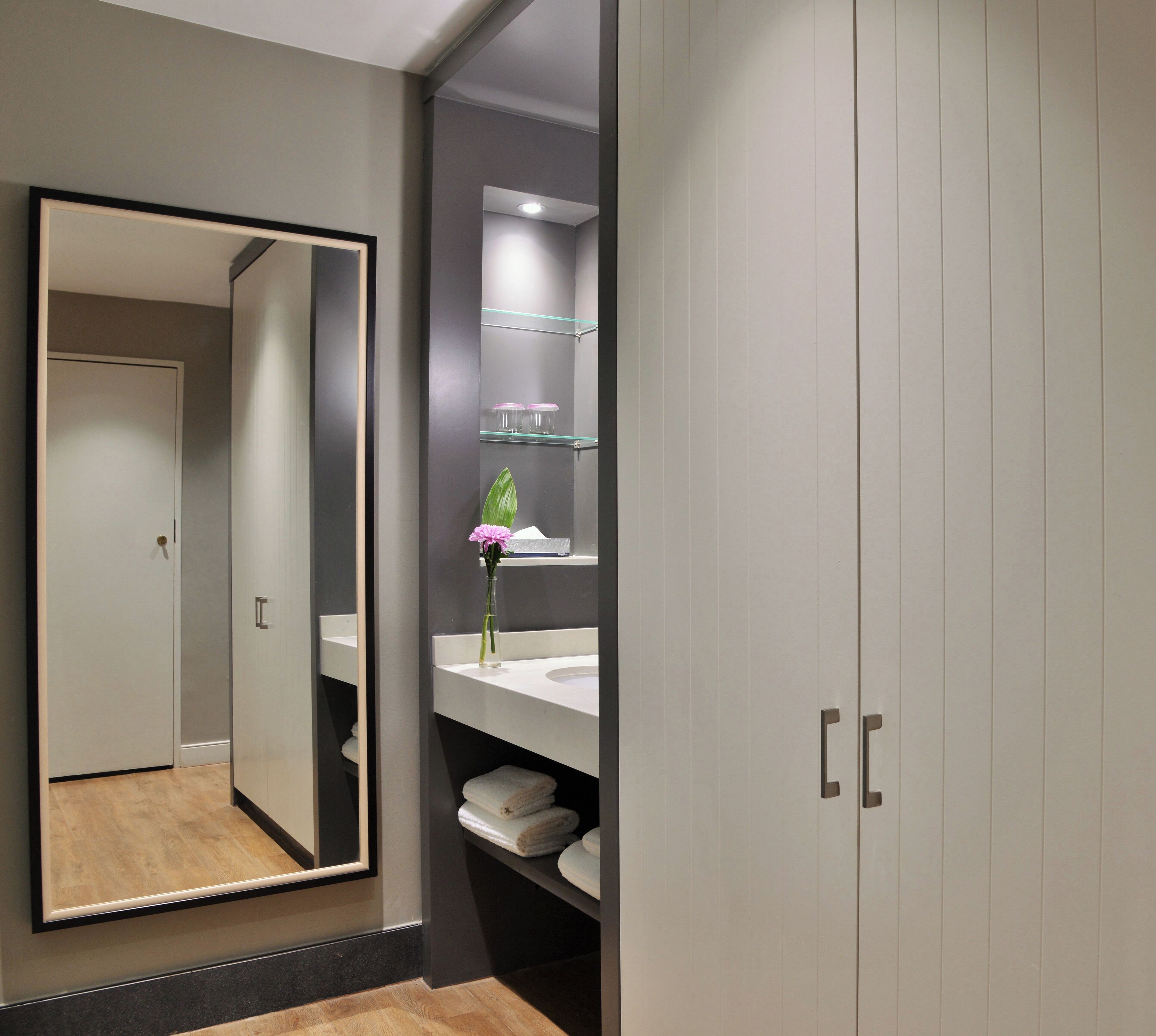 Een moderne badkamer met een grote spiegel, een wastafelmeubel en een kast met lades.
