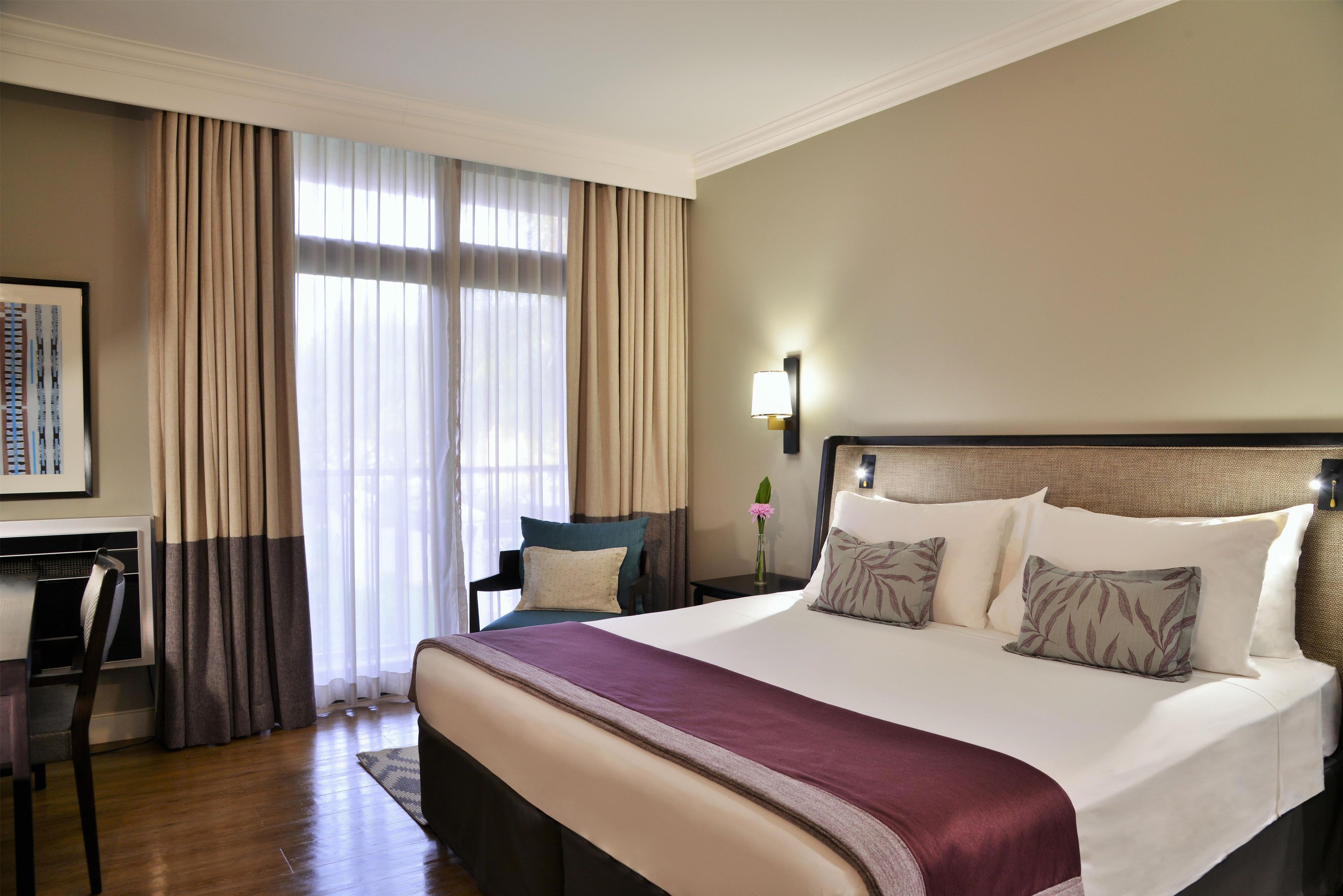Une chambre d’hôtel avec un grand lit, un bureau et une chaise.