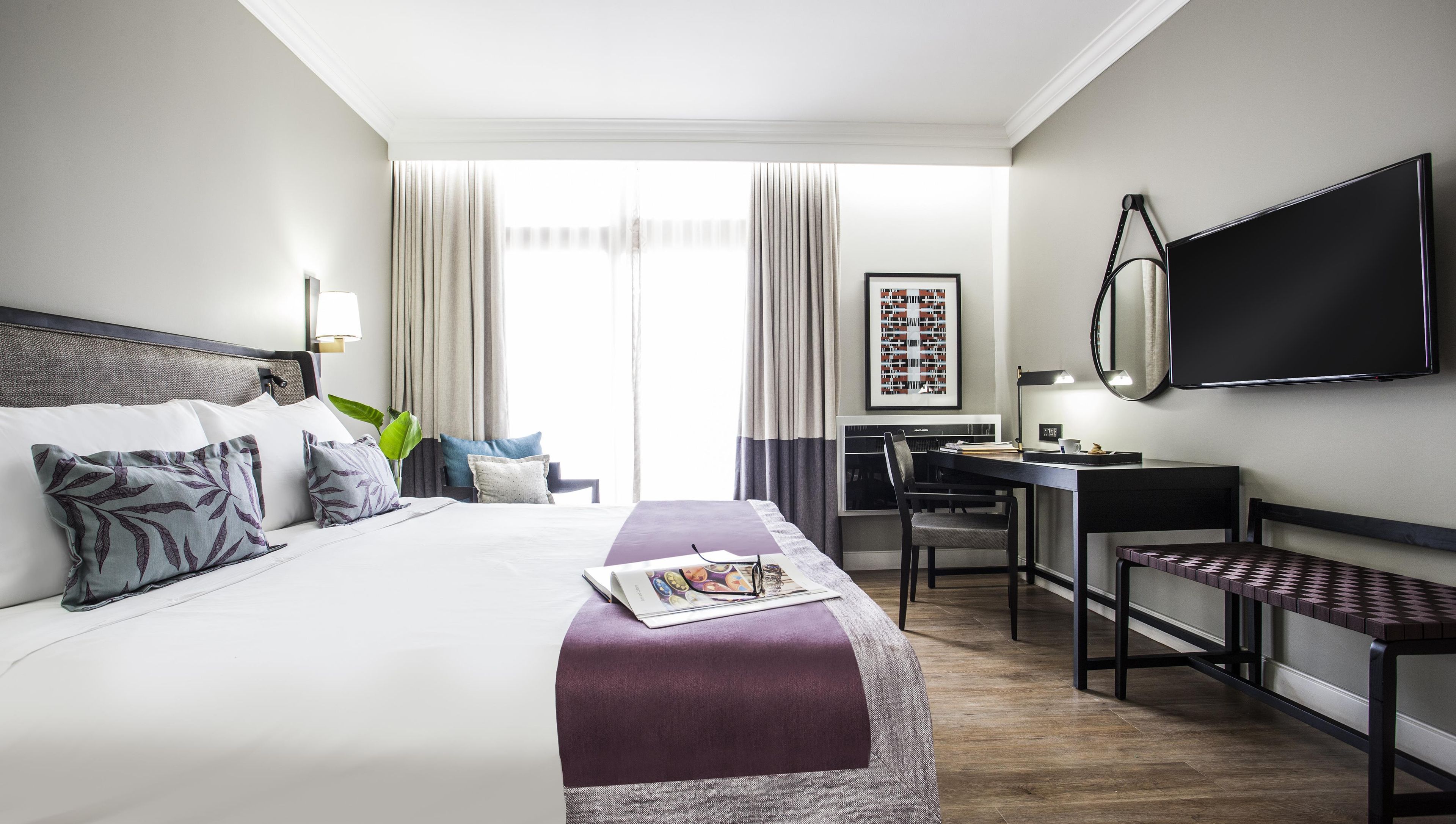 Una habitación de hotel con cama, escritorio, silla y televisión de pantalla plana.