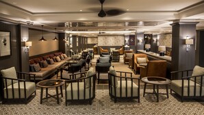 A spacious lounge area with multiple seating options including sofas, armchairs, and a long communal table. - Avani Gaborone Resort & Casino (Gaborone)