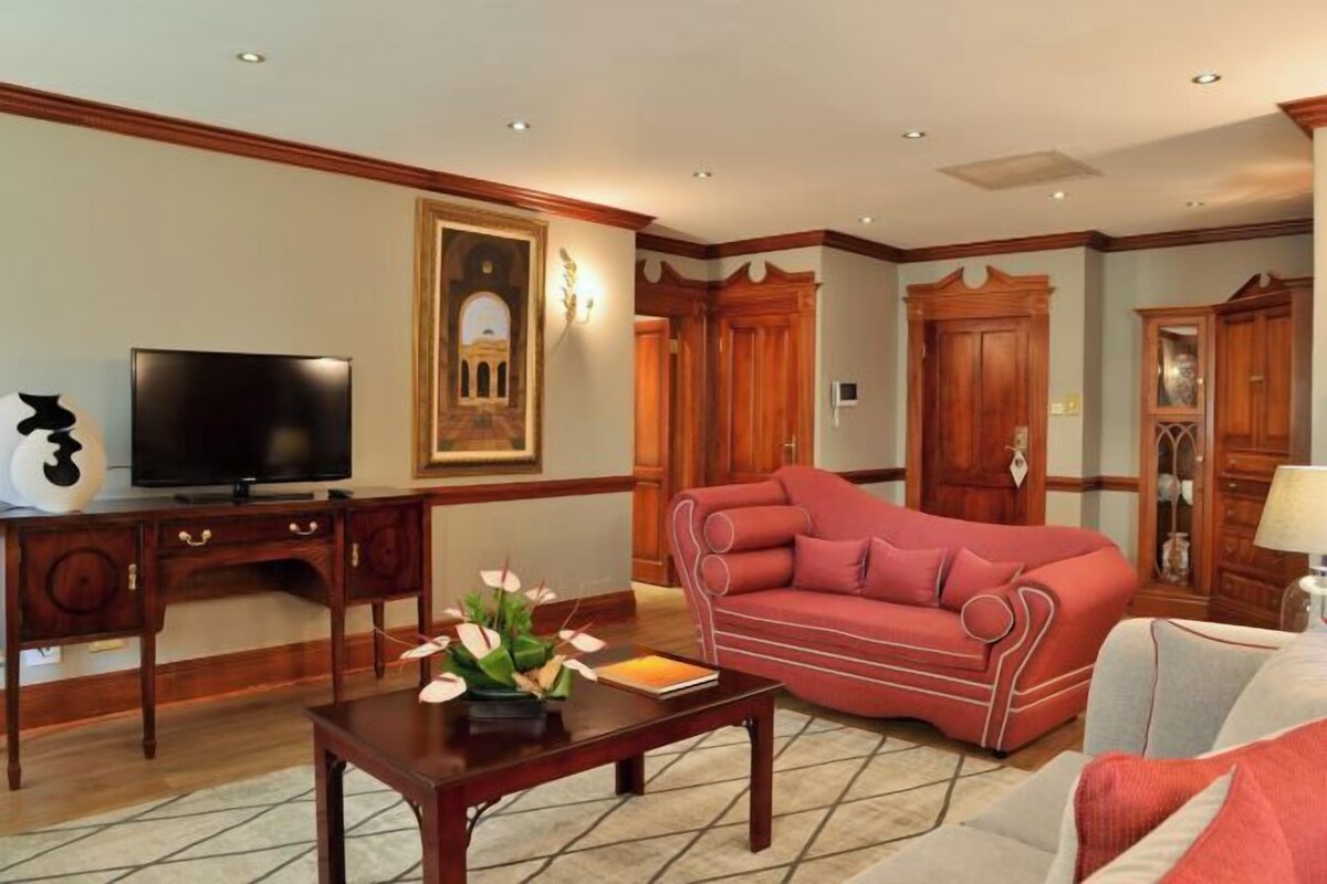 A living room with a red sofa, a television, wooden cabinets, and a decorative wall piece.