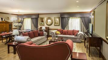 A spacious living room with a sofa set, a dining area with a piano, and a television on a wooden stand.