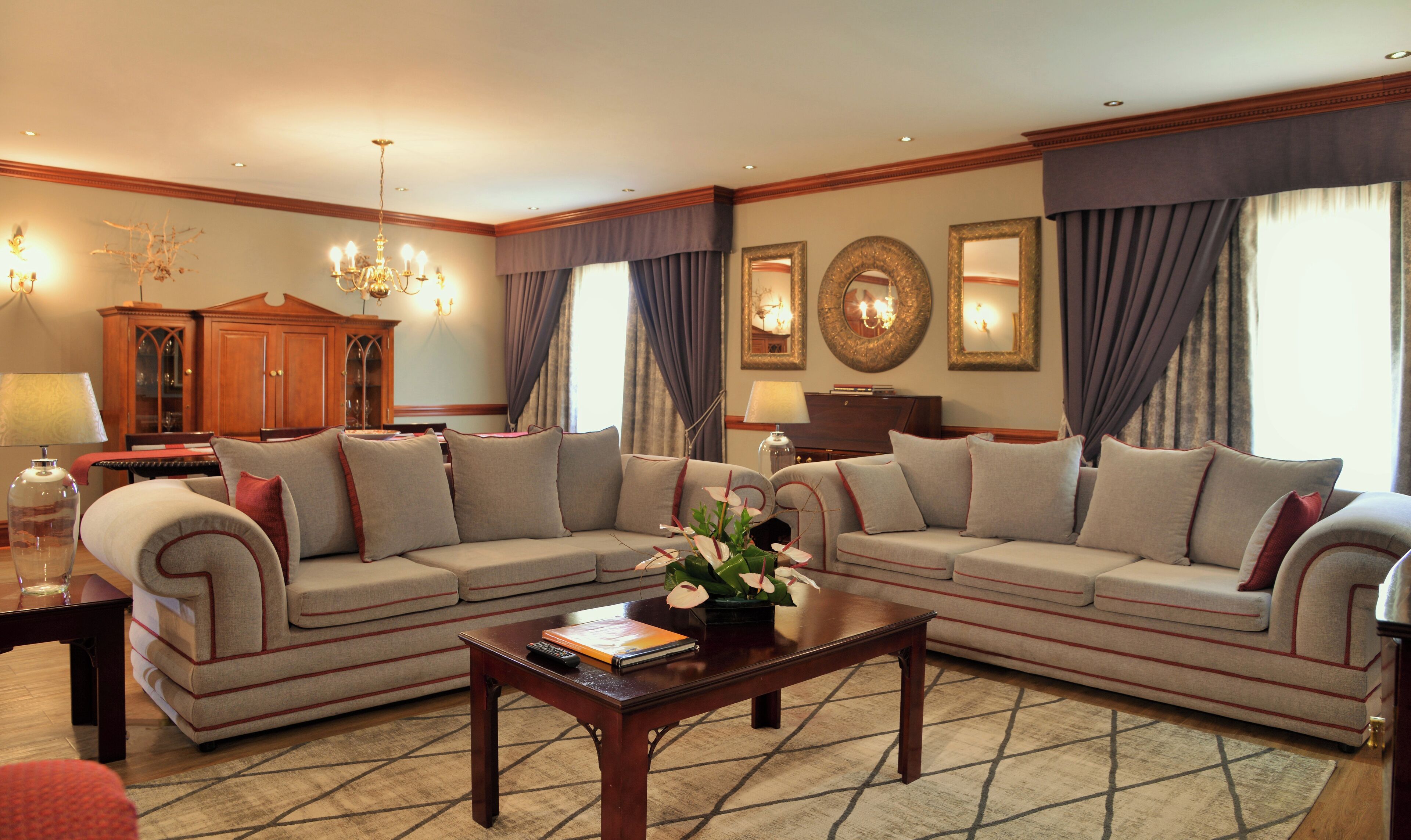 A living room with a sectional sofa, a coffee table, a chandelier, and a cabinet.