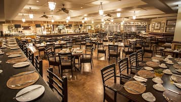 Un restaurante espacioso con varias mesas y sillas, una zona de bar y ventiladores de techo.