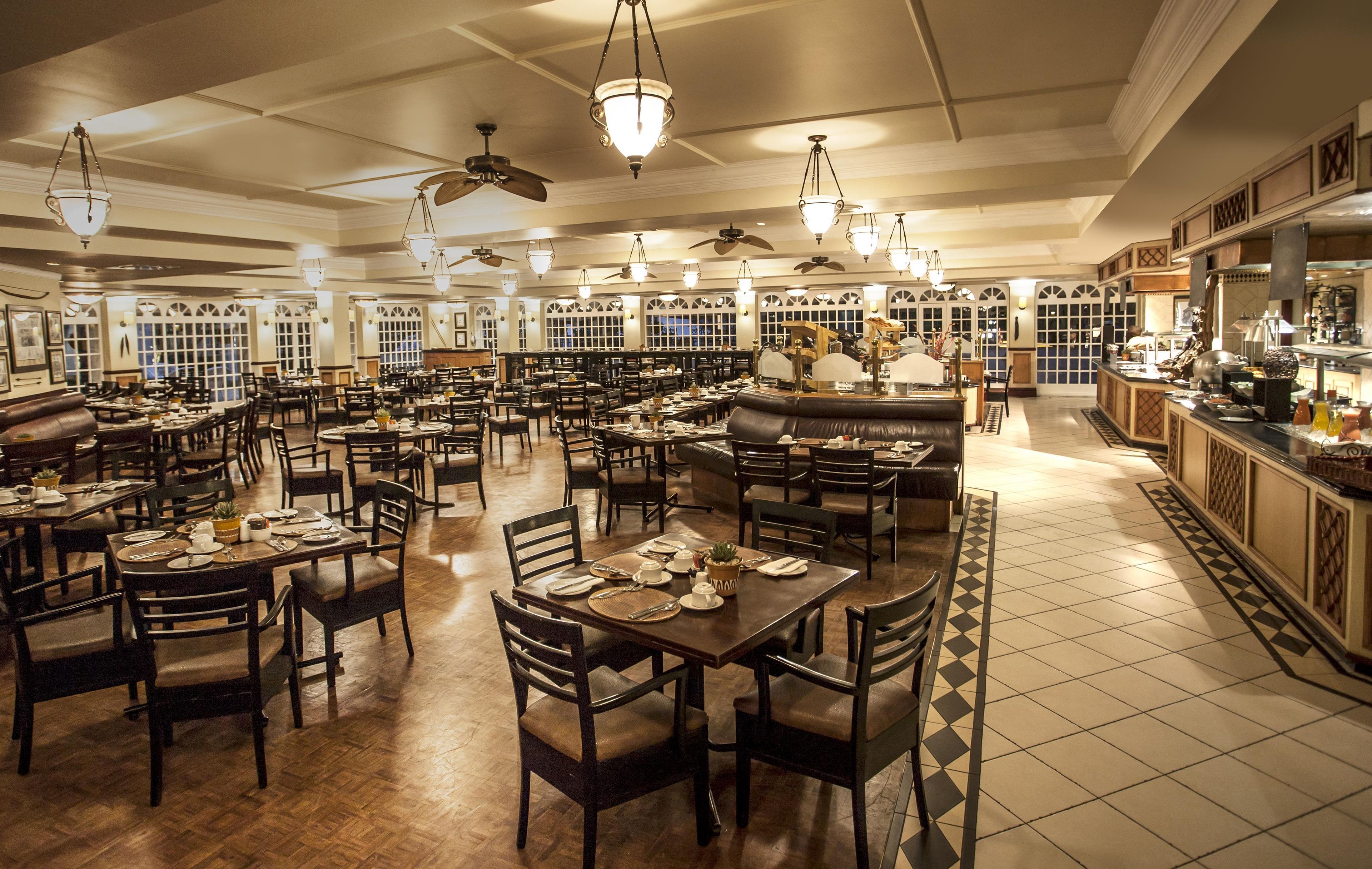 A spacious restaurant with multiple dining tables and chairs, ceiling fans, and a variety of lighting fixtures.