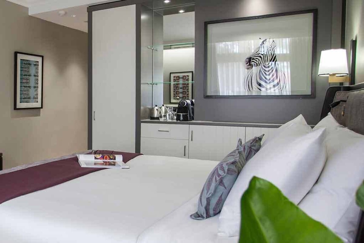 Habitación de hotel con cama, escritorio, silla, televisor y un espejo grande.