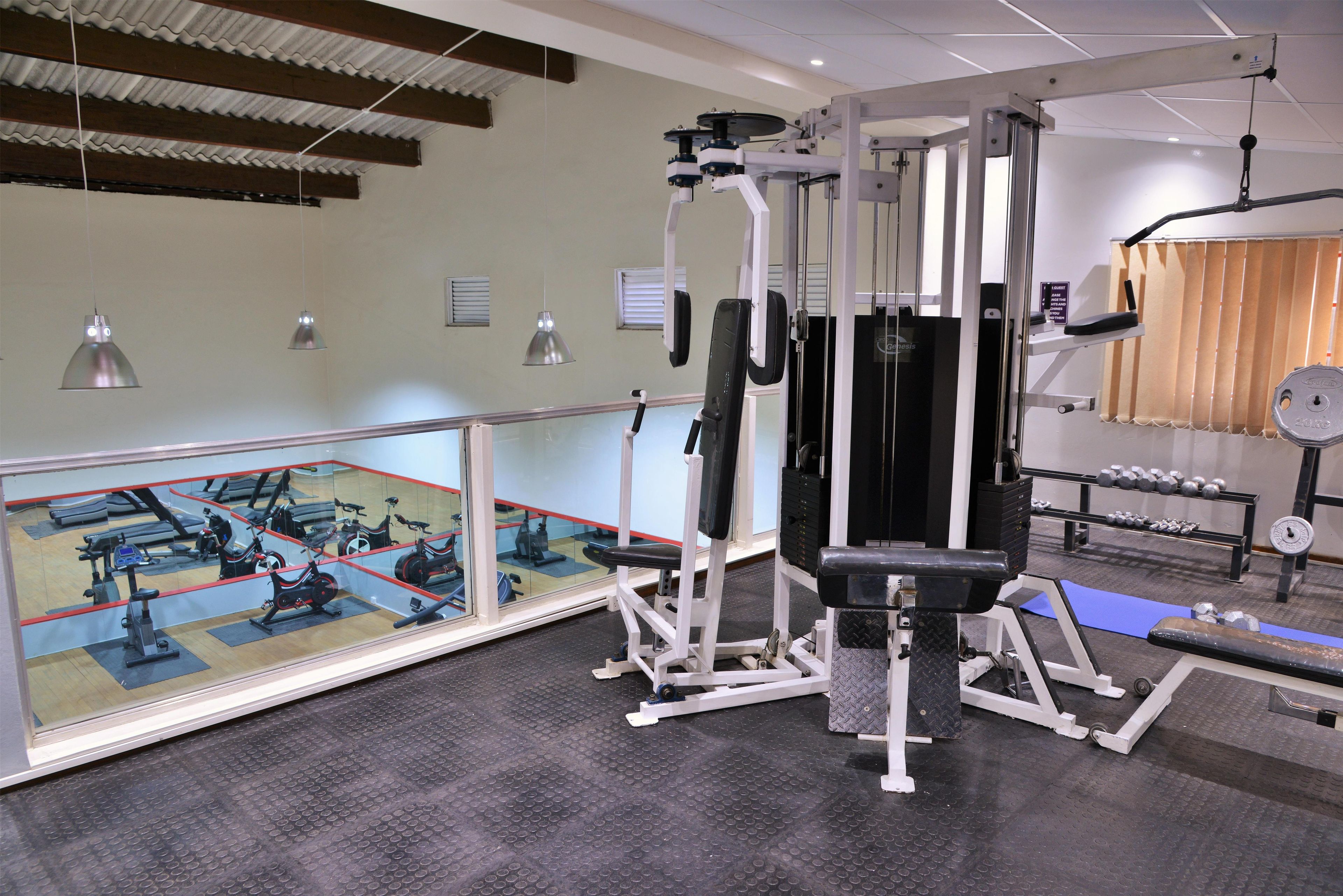 A gym with exercise equipment, a mirrored wall, and a weight rack.