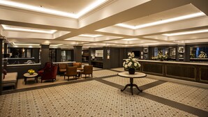 A spacious lobby with a patterned floor, a reception desk, seating area, and a decorative vase with flowers. - Avani Gaborone Resort & Casino (Gaborone)