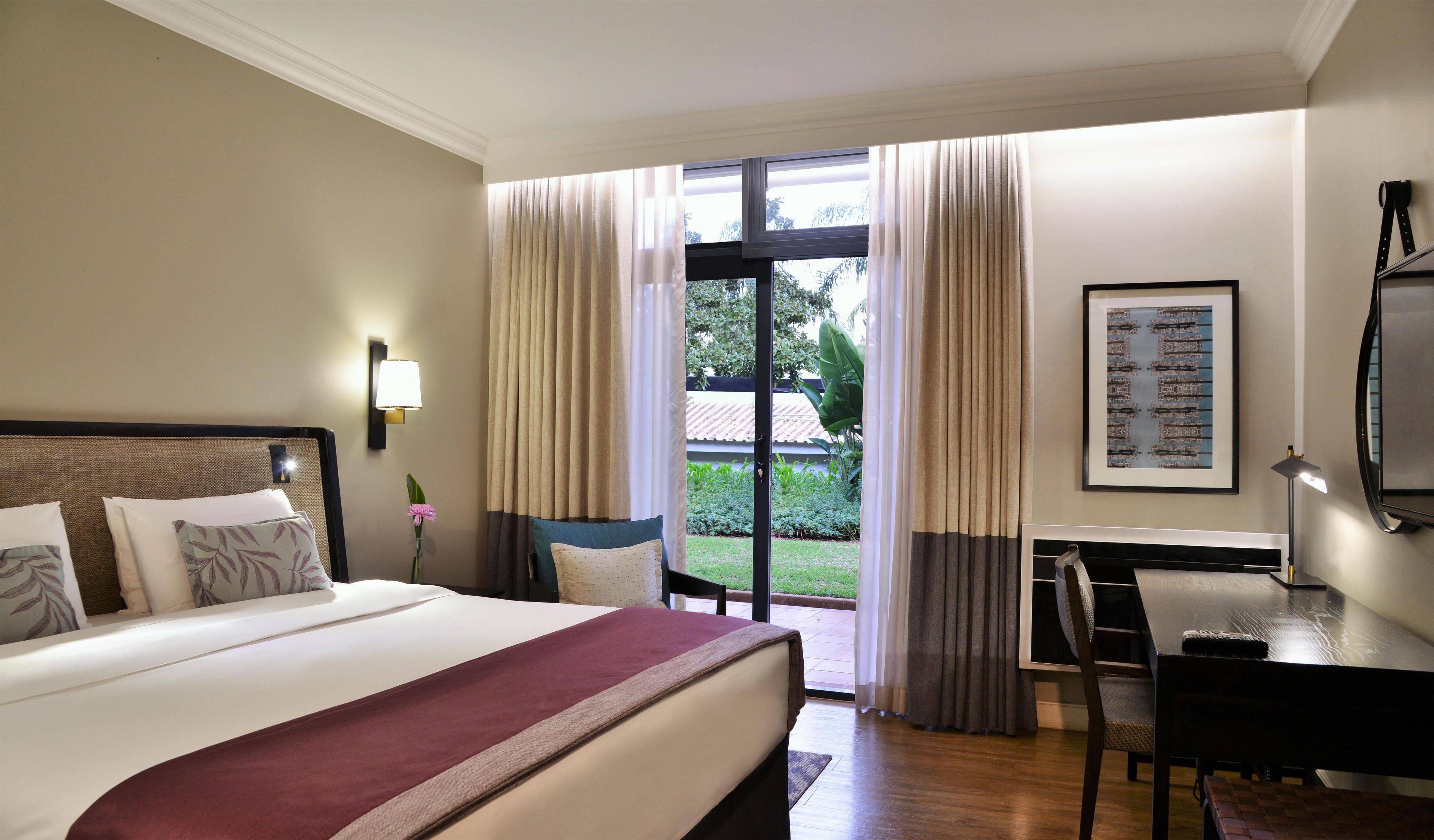 Une chambre d’hôtel équipée d’un lit, d’un bureau, d’une chaise, d’une télévision et d’une fenêtre avec des rideaux.