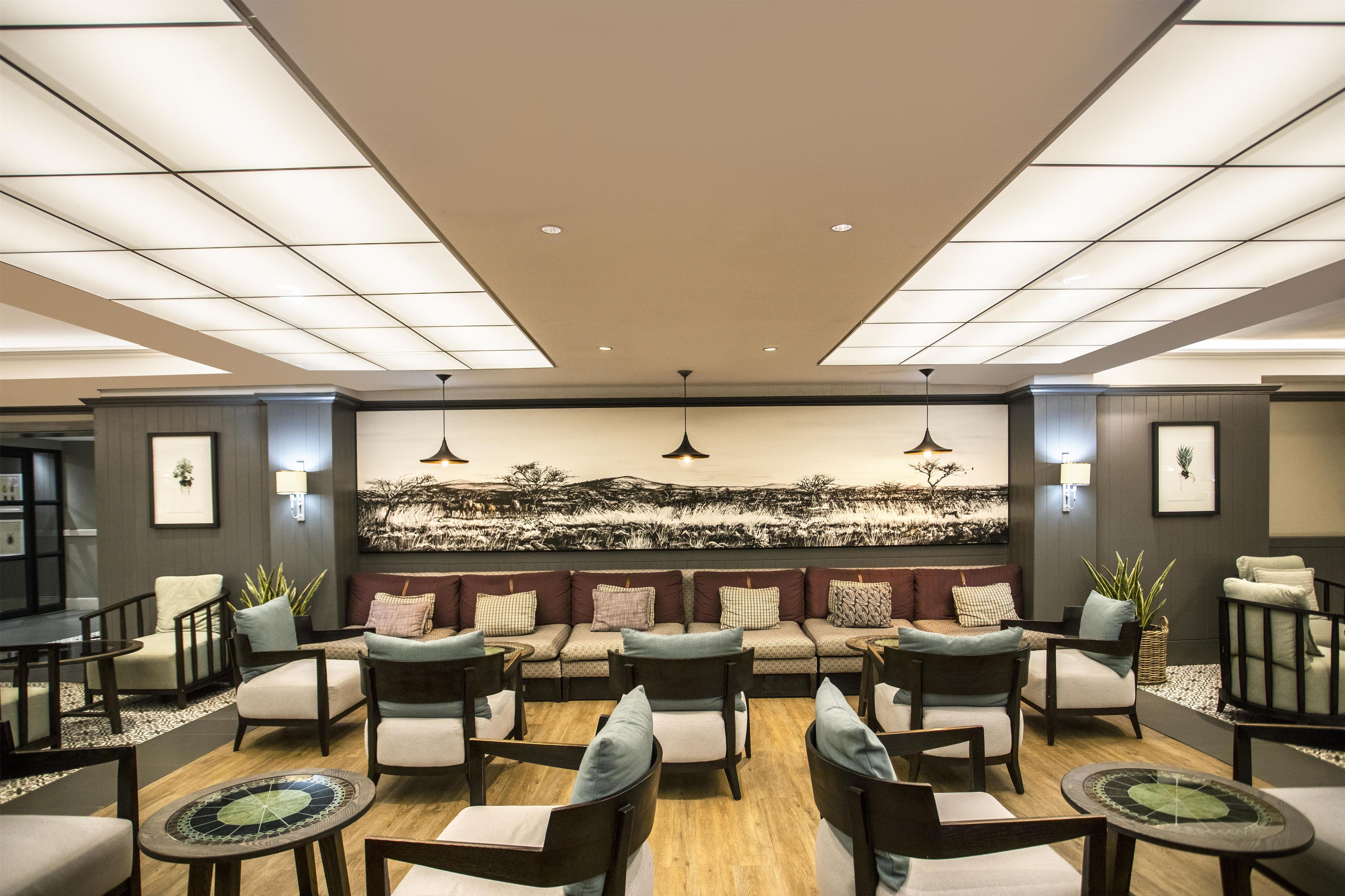 A modern lounge area with a high ceiling, recessed lighting, and a large wall mural.