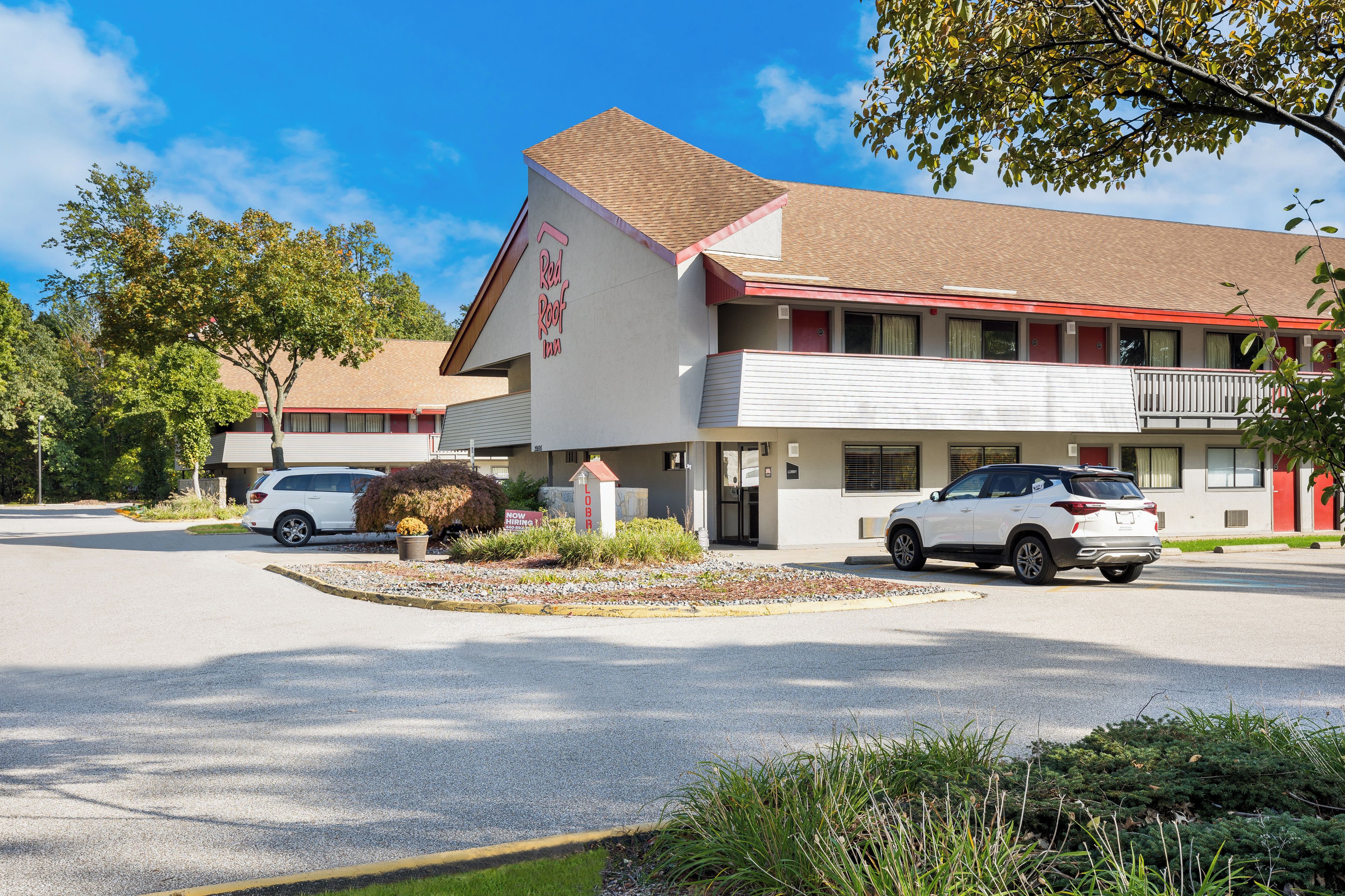 Een Red Roof Inn met een gebouw van twee verdiepingen, een parkeerplaats en een aangelegde entree.
