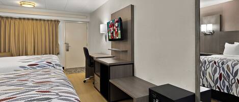 A hotel room with a bed, desk, chair, TV, and a mirror.