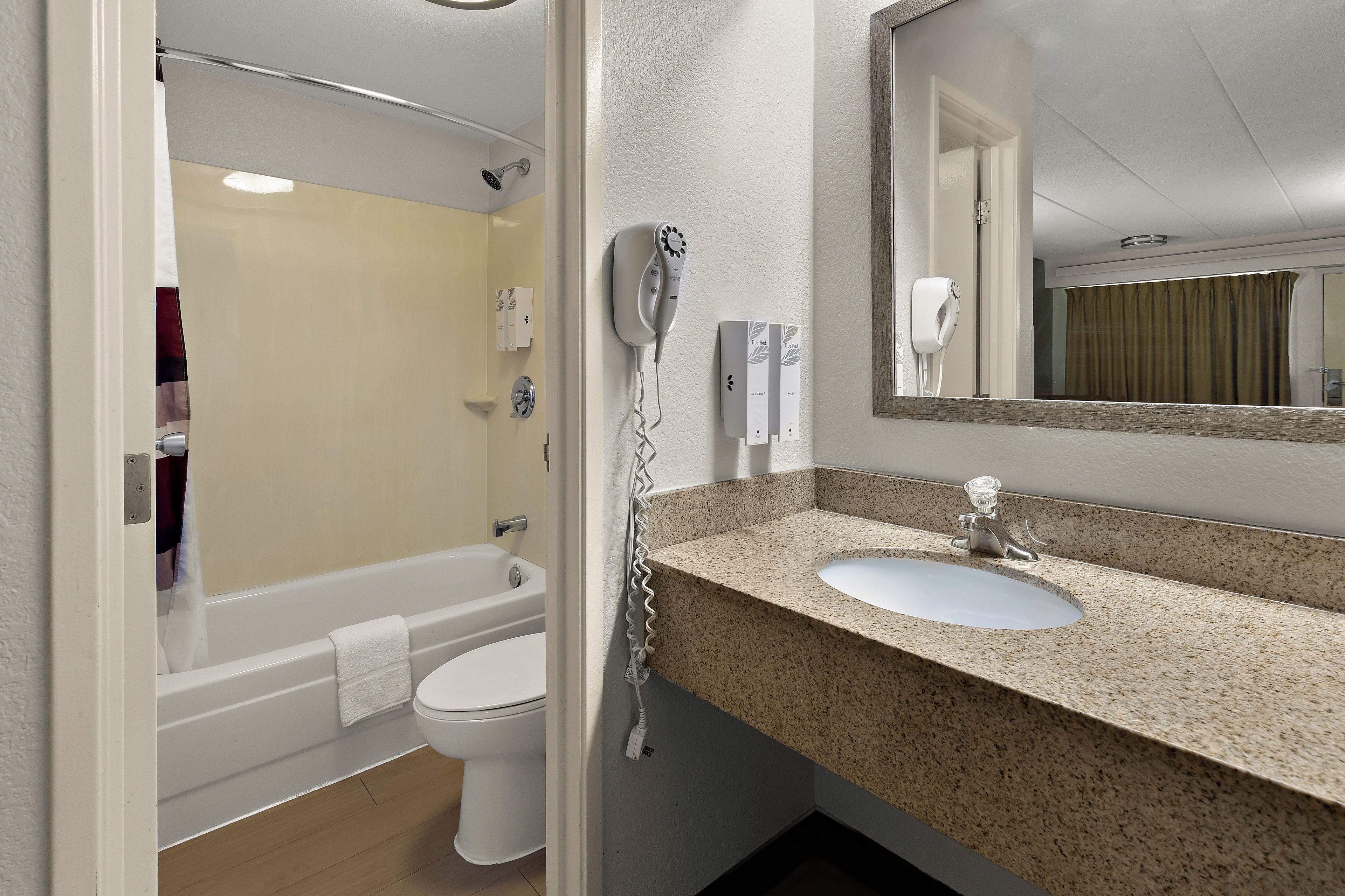 A bathroom with a bathtub, toilet, and a sink with a granite countertop.