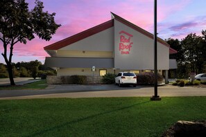 A Red Roof Inn with a parking lot, a white car parked in front, and a clear sky. - Red Roof Inn Cleveland - Westlake (Westlake)
