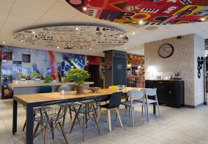 A restaurant with a central dining area, a brick wall with a clock, and a ceiling with a circular design.