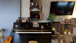 A piano, a guitar, a television, and a brick wall. - B&B Hotel Reims Centre Erlon (Reims)