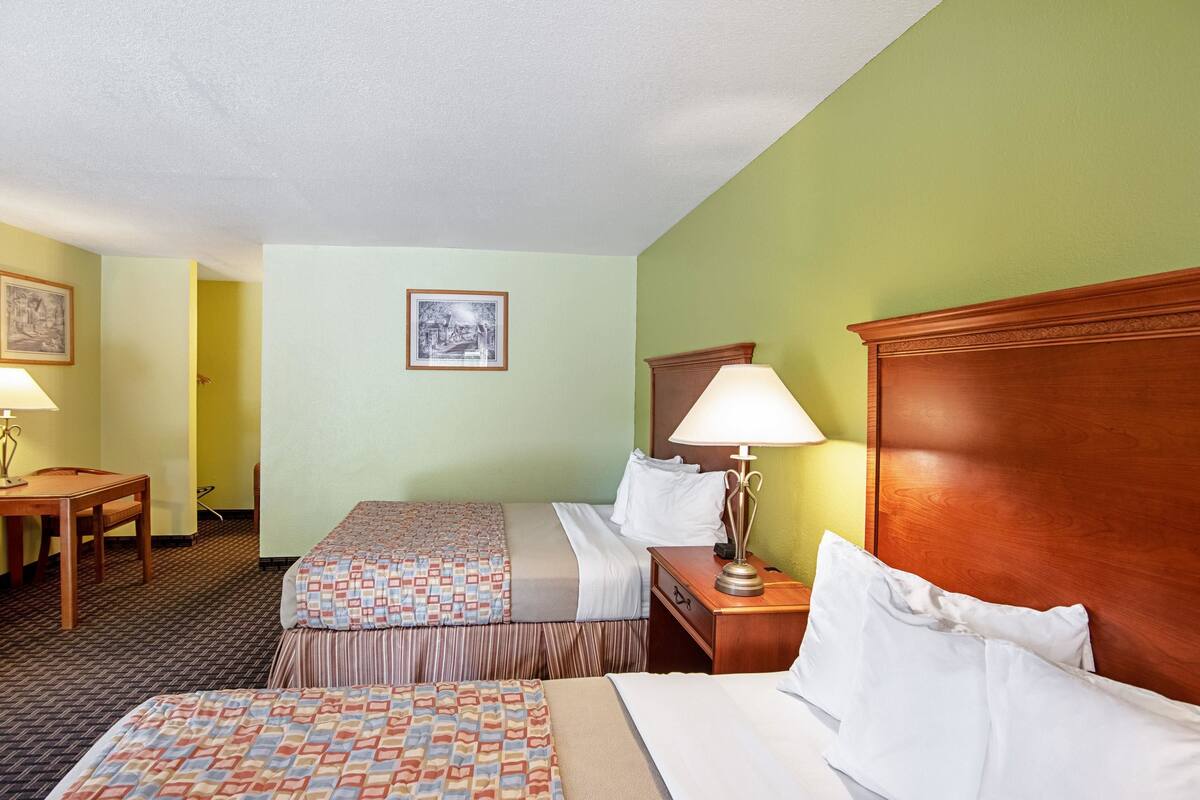 Une chambre d’hôtel avec deux lits, un bureau et une chaise.