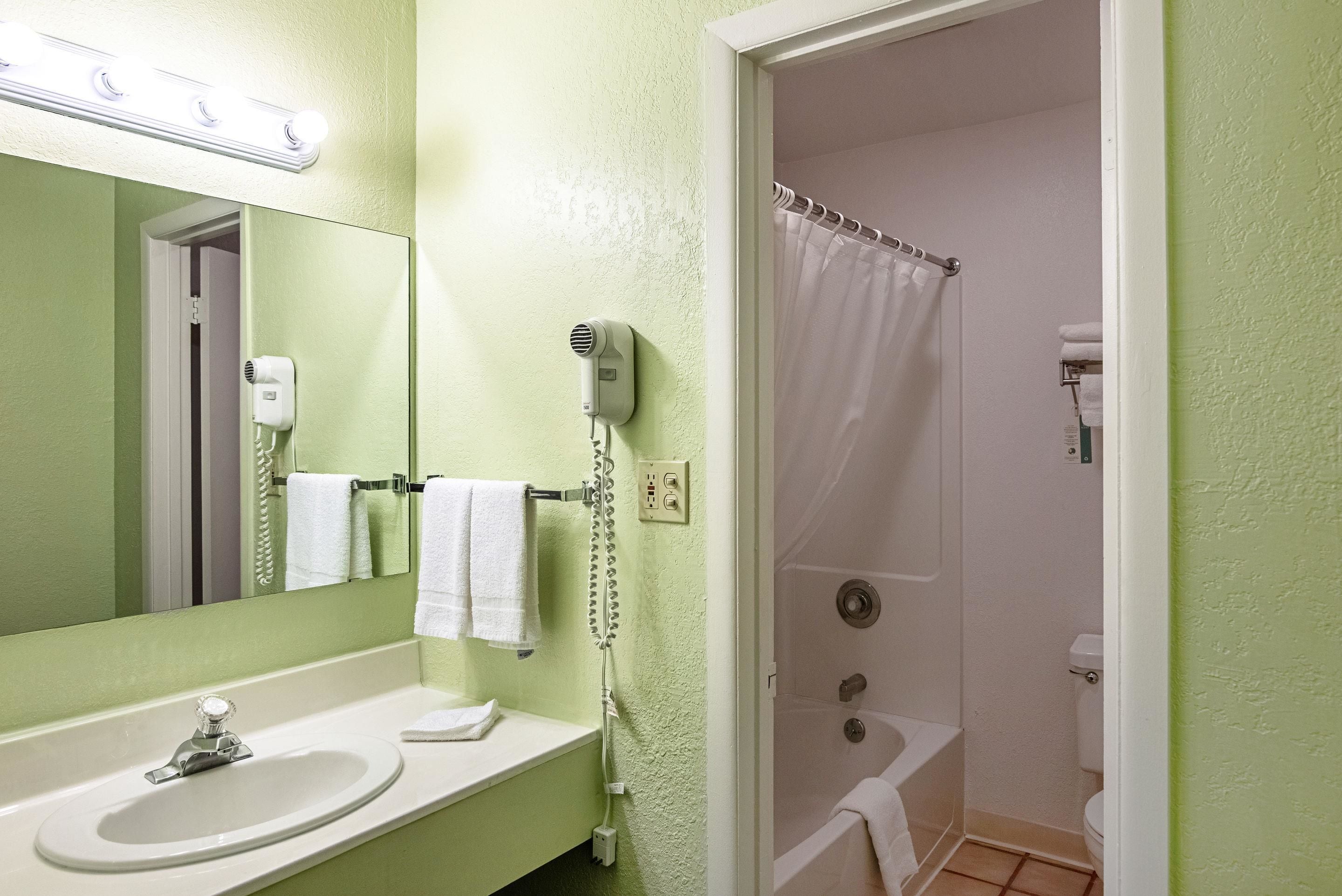 Un baño con lavamanos, espejo y zona de ducha.