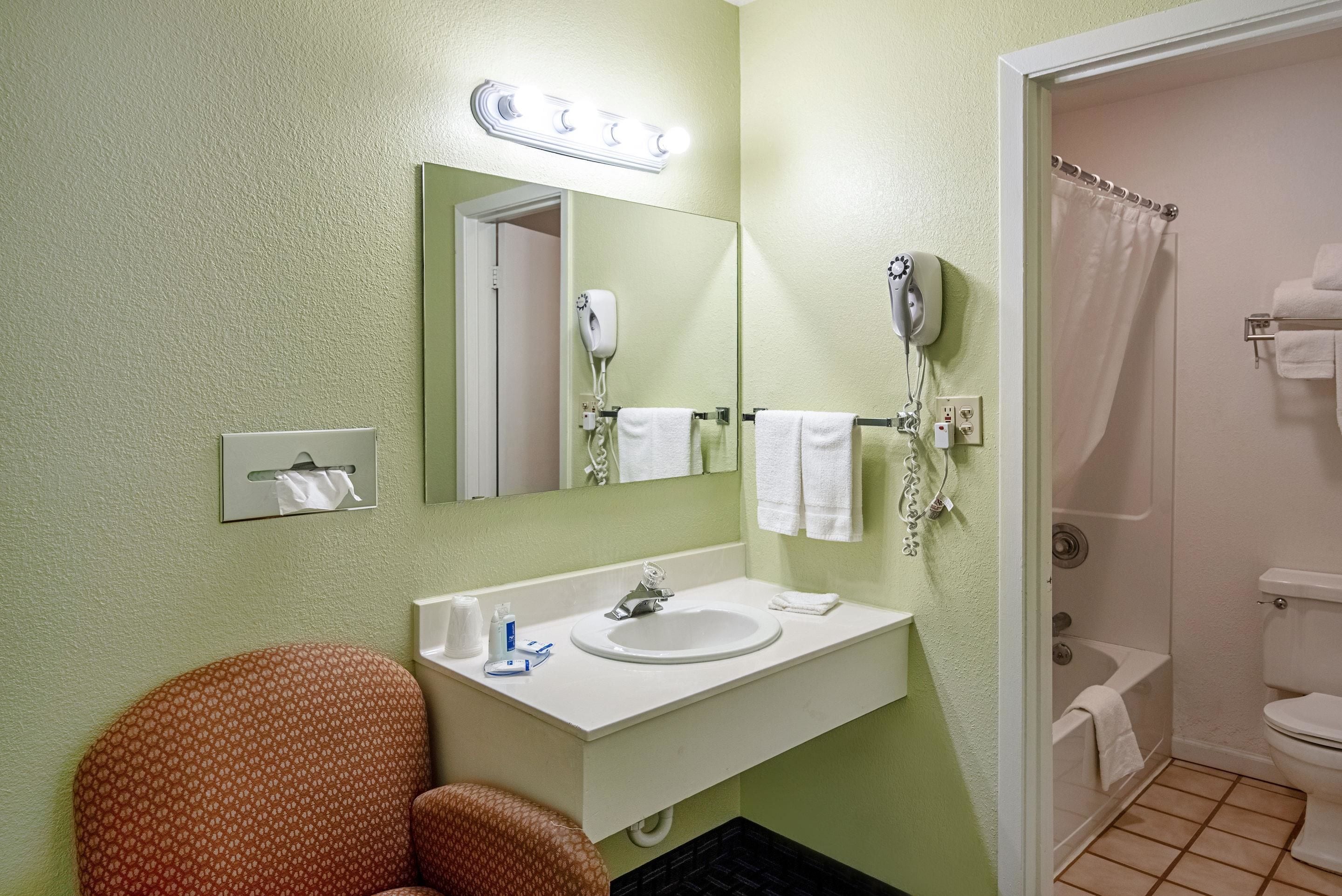 A bathroom with a sink, mirror, towel rack, and shower.