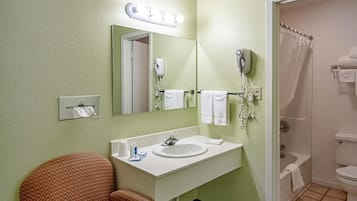 A bathroom with a sink, mirror, towel rack, and shower.