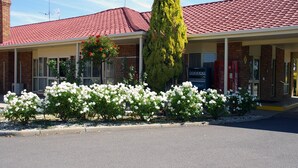 A building with a red-tiled roof, a brick facade, and a covered porch with white railings. - Pines Country Club Motor Inn (Shepparton)