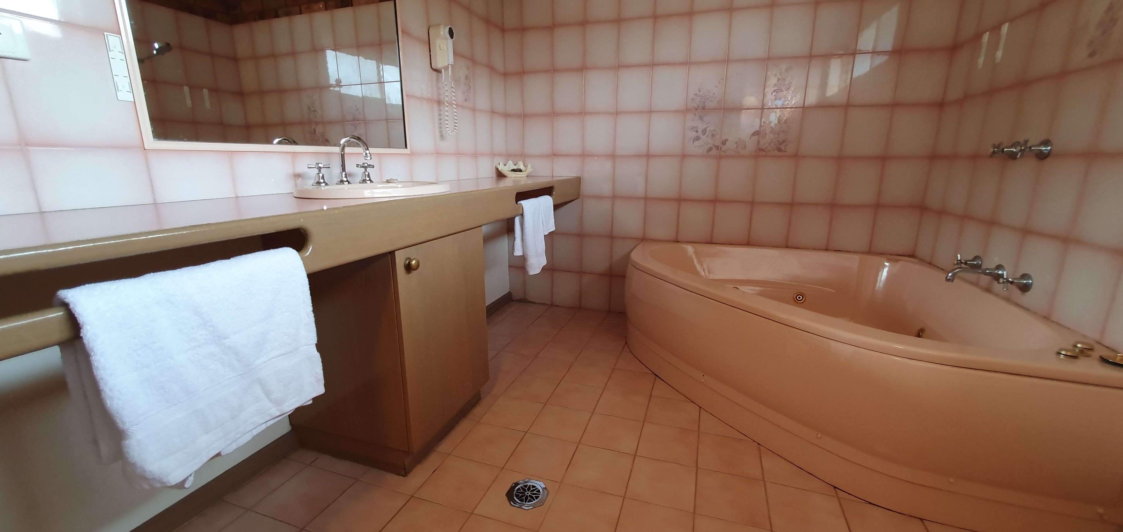 A bathroom with a beige sink, mirror, and bathtub.