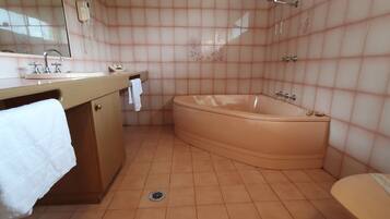 A bathroom with a bathtub, a sink with a mirror, and a toilet.