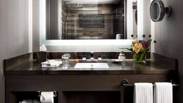 A modern bathroom with a dark wood vanity, a large mirror, and a built-in shower.
