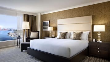 A hotel room with a large bed, two bedside tables, a chair, and a view of the water.