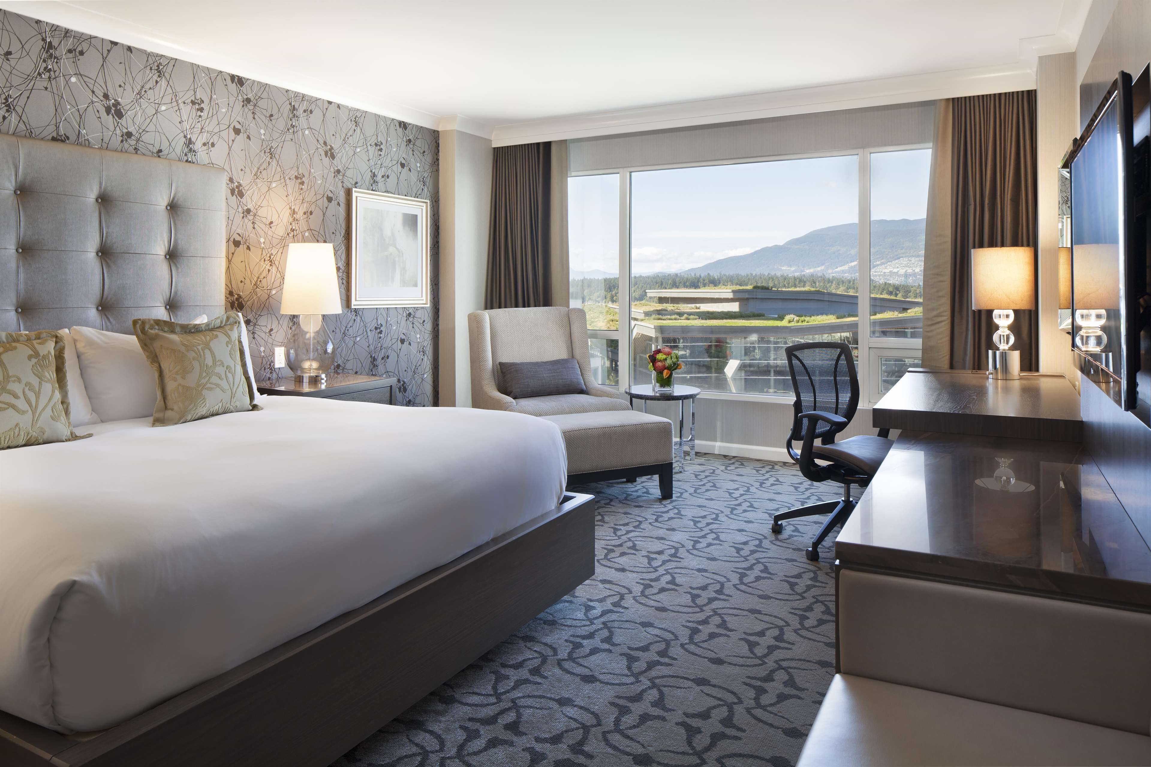 Une chambre d’hôtel avec un grand lit, un bureau, une chaise et une vue sur l’extérieur.