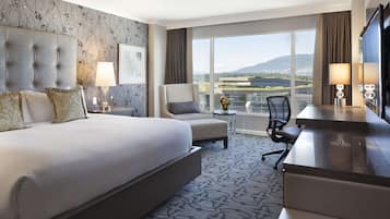 Une chambre d’hôtel avec un grand lit, un bureau, une chaise et une vue sur l’extérieur.