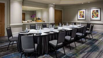 A conference room with a long table, chairs, and a buffet area in the background.