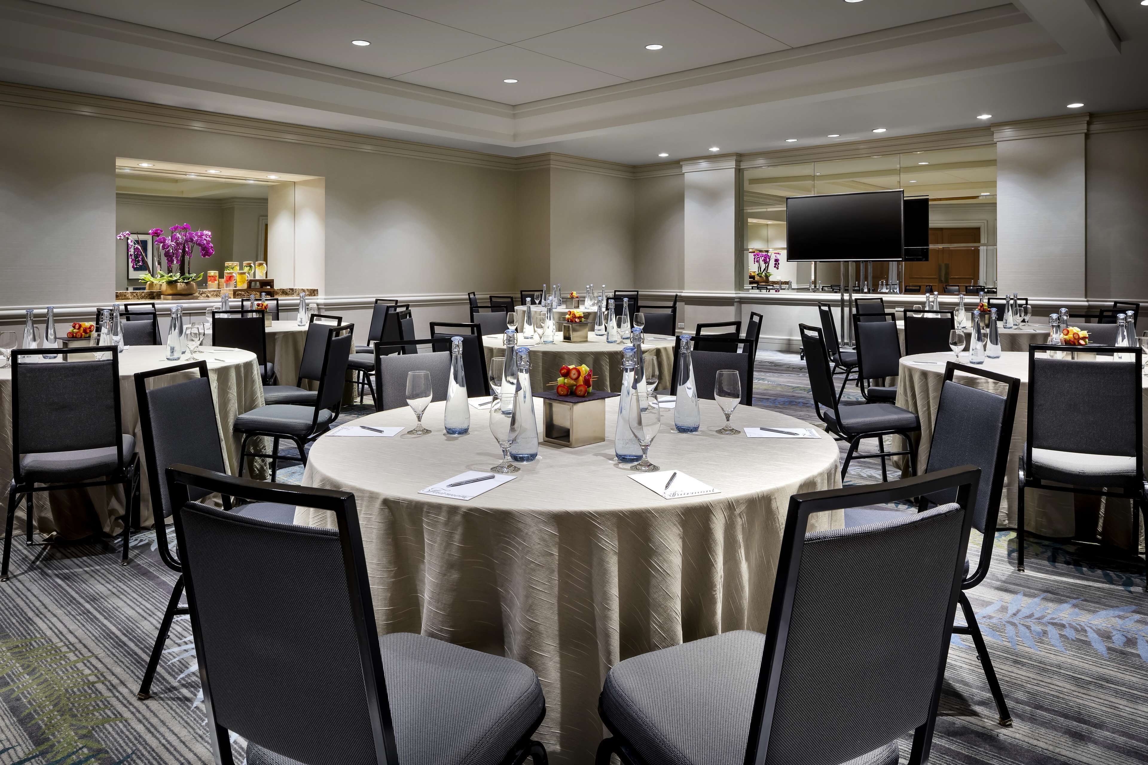 A conference room with round tables, chairs, and a large flat-screen TV.