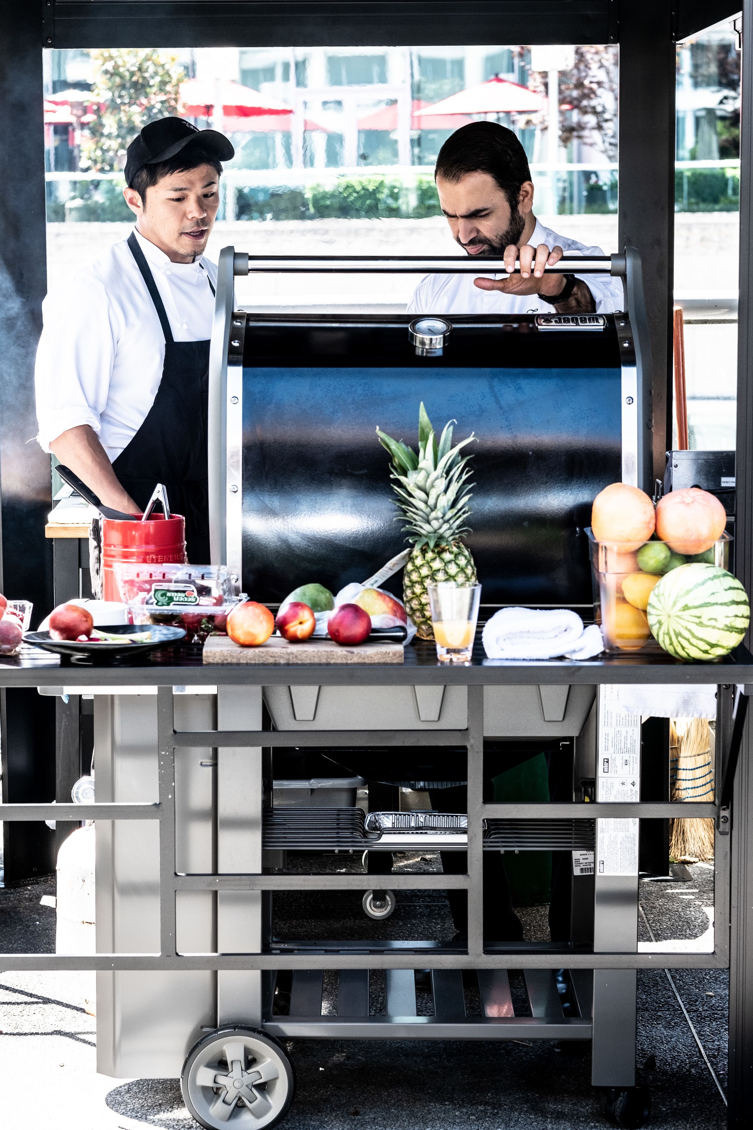 A food cart with a variety of fruits and a beverage.