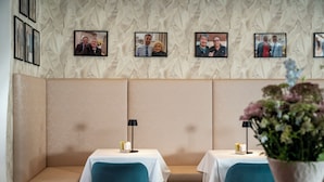 Interior de restaurante con asientos tipo cabina, mesas con manteles blancos y fotografías enmarcadas en la pared.