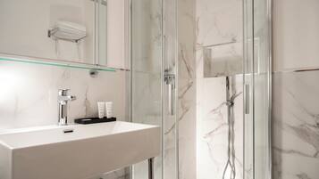 Un baño moderno con cabina de ducha de vidrio, un lavabo blanco y un espejo sobre él.