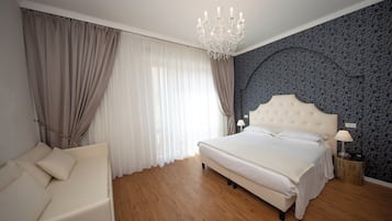 Een slaapkamer met een groot bed, een kroonluchter, een nachtkastje en een bank.