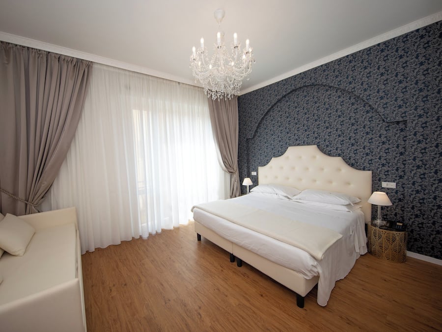 Camera da letto con un letto grande, un lampadario, un comodino e un divano.