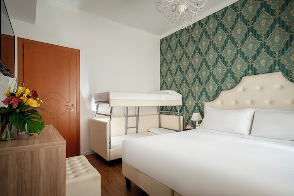 A hotel room with a bunk bed, a bedside table, a lamp, and a decorative wall.