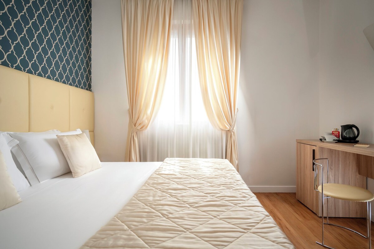 Una habitación de hotel con una cama, un escritorio y una silla.